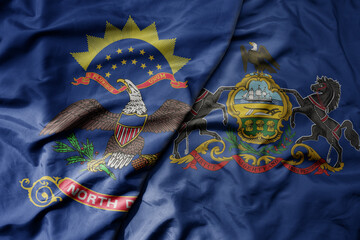 big waving colorful national flag of pennsylvania state and flag of north dakota state .