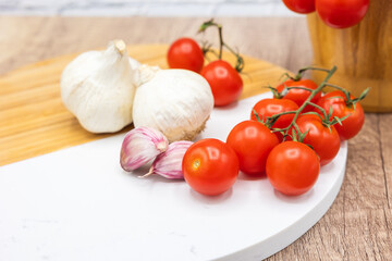 ingredients in the kitchen, vine cherry tomatoes with garlic on a wooden and stone board