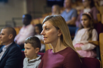 Obraz premium Portrait of interested woman theatergoer absorbedly watching stage performance in theater