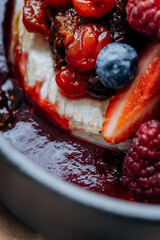 Tasty baked Camembert brie cheese with cranberry sauce and berries in restaurant. Gourmet appetizer