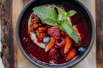 Tasty baked Camembert brie cheese with cranberry sauce and berries in restaurant. Gourmet appetizer