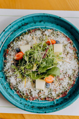Beef carpaccio with pesto sauce and parmigiano cheese decorated by salad and fruit. Restaurant menu