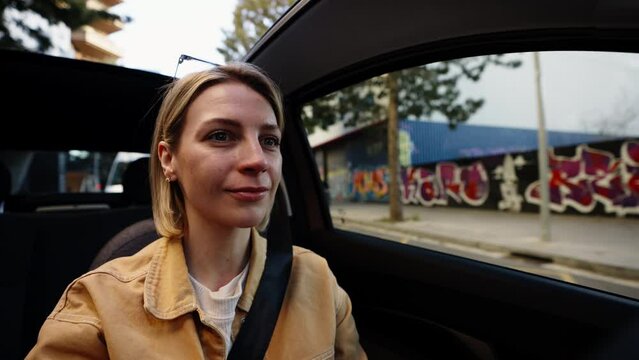 Blonde woman driving convertible with urban graffiti in the background, reflecting contemporary city life and culture