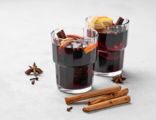 Mulled wine with orange, apple and cinnamon in glasses on a light background. The concept of a traditional winter hot drink with spices and fruits.