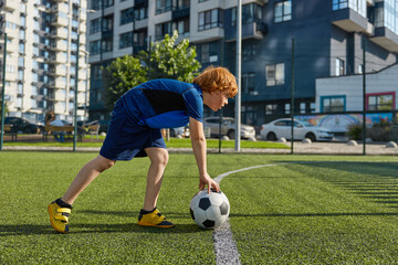 Obraz premium Boy child putting ball on strip line on football field, start game match