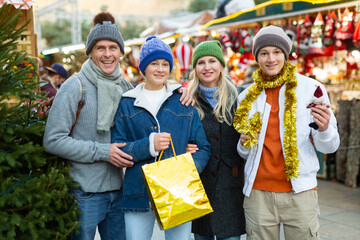 Cheerfull family with two teenagers posing with christmas gifts at Xmas market - obrazy, fototapety, plakaty