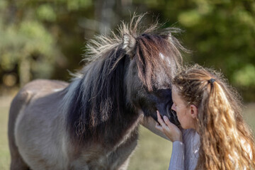 Natural Horsemanship concept: Cute portrait of a young woman and her pony working and interacting together