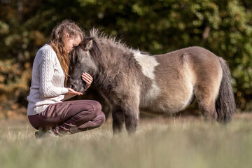 Natural Horsemanship concept: Cute portrait of a young woman and her pony working and interacting...