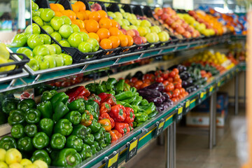 Stand of boxes full of fresh colorful fruits and vegetables in big grocery store - obrazy, fototapety, plakaty