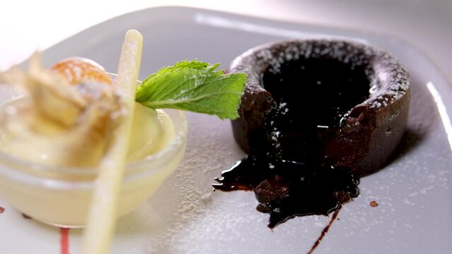 chocolate fondant on white plate with dark chocolate ice cream strawberries drops of syrup beautiful serving in an expensive restaurant. dessert food