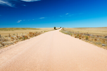 Dirt road in the country stretches into the distance under a blue sky in South Australia