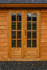 Massive wooden entrance doors with round handles and small keyhole close up. Double doors in solid wood in natural wooden color