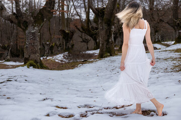 woman in a white lace dress walking barefoot through a snowy forest, creating a peaceful and serene mood