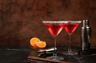 Festive alcoholic cocktail with red martini, lemonade, champagne in glasses on a dark background,...