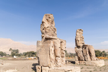 Massive ruined stone Pharaoh statues at Colossi of Memnon in Luxor, Egypt