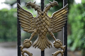 Double-headed eagle national symbol, gold colored metal on the iron grate of a state institution....