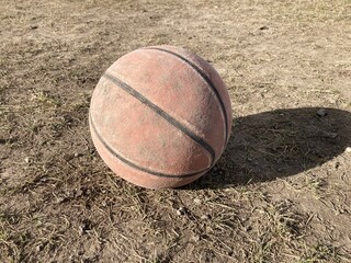 Old dirty basketball in dusty field
