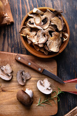 Food photography background - Fresh and dried forest mushrooms in woode bowl and cutting board with knife on table. View from above.