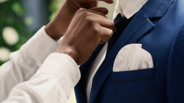 Precise retail clerk working in luxury fashion boutique, arranging pocket square on blazer. African american employee showcasing new collection of trendy garments on mannequin, extreme close up shot