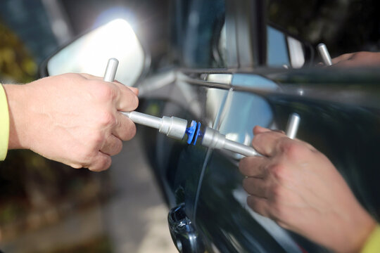 The process of removing dents from the car side  at the service station,. Repairing car dent after the accident