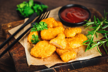Chicken Breaded Raw Meat.Fast food.Fast cooking.Chicken nuggets with salad.Semifinished Breaded chicken nuggets from chicken fillet on a dark background with fresh herbs. Quick cooking at home.