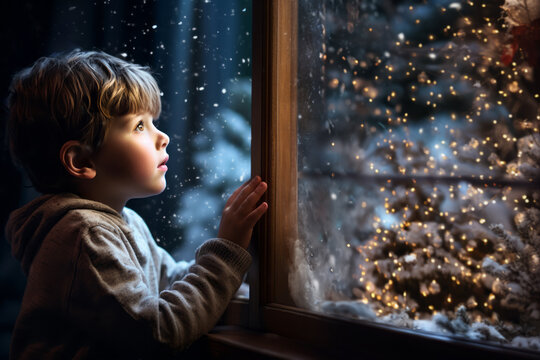Childhood wonder: Joyful kid looking out of window at snowflakes fall and magical christmas tree