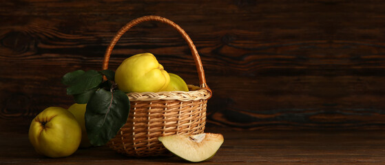 Wicker basket of sweet ripe quinces on wooden background with space for text