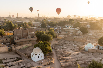hot air balloons floating over dusty desert villages in luxor egypt