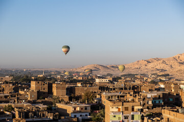 hot air balloons floating over dusty desert villages in luxor egypt