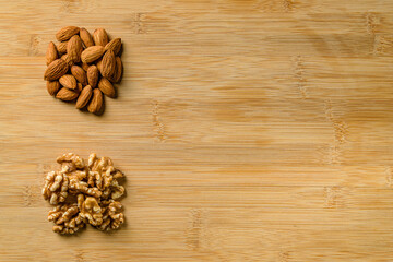 Raw almonds and walnut halves on the wooden cutting board backgr