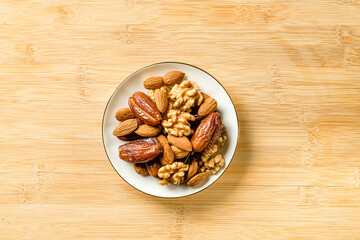 Raw almonds, organic pitted dates and walnut halves in a white p