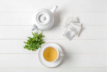 Fototapeta na wymiar Teapot with cup of fresh mint tea on white wooden background