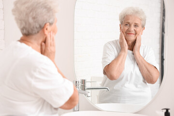 Senior woman looking in mirror at home