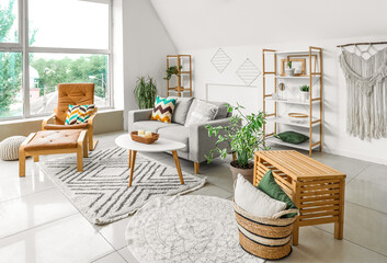 Interior of light living room with plants, sofa and armchair