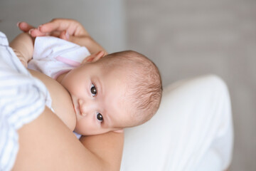 Young woman breastfeeding her baby at home, closeup