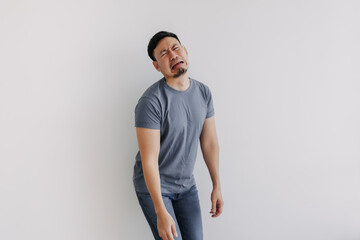 Sad funny face asian man in blue t-shirt crying stand isolated on white.