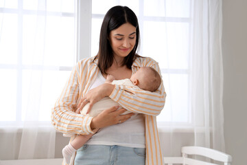 Young woman with her sleeping baby in bedroom