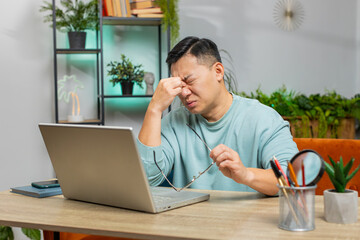 Displeased sad Asian man use laptop notebook typing browsing working, loses becoming surprised...