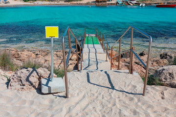 Stainless steel ladder placed on a beach, specifically near a swimming area