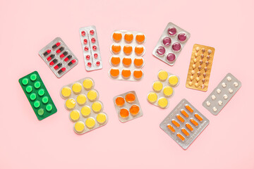 Different pills in blister packs on pink background