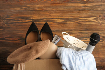 Box of unwanted stuff for garage sale on brown wooden background
