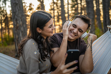 Man and woman young adult couple in nature listen music headphones