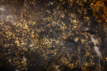 plástico negro manchado con polvo dorado