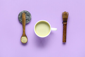 Cup of fresh matcha tea, powder and chasen on lilac background