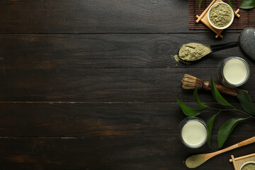 Composition with cups of fresh matcha tea, powder and accessories on dark wooden background