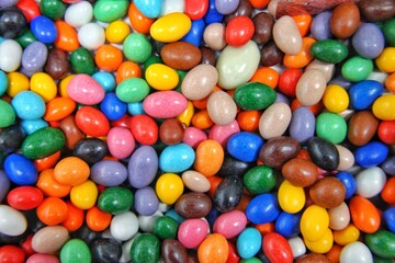 Round multi-colored candy balls lie mixed up solid background