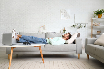 Young bearded man lying on sofa at home