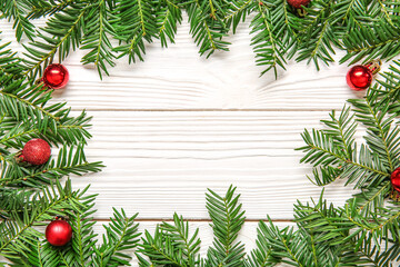 Naklejka na ściany i meble Frame made of fir branches and Christmas balls on light wooden background