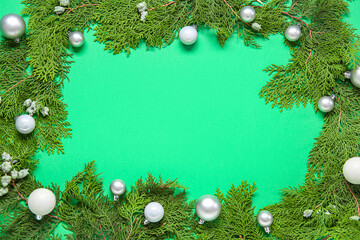 Frame made of thuja branches and Christmas balls on green background