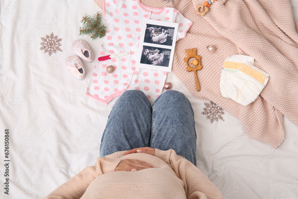 Sticker pregnant woman with sonogram image, baby accessories and christmas decorations on bed